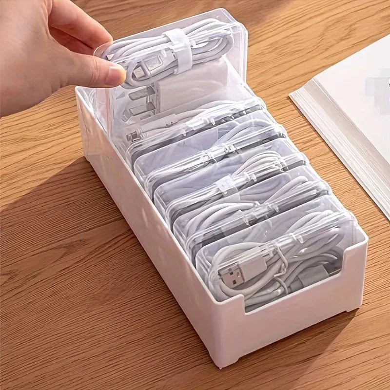 GridLogic transparent desktop cable storage box with 7 compartments showing neatly coiled USB chargers and data cables.